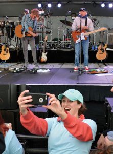 Person taking selfie with band playing in background