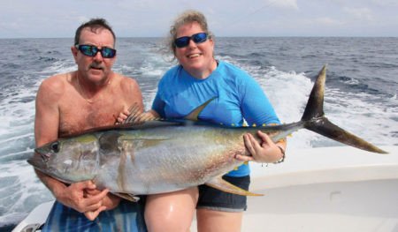 Man and woman holding a large tuna