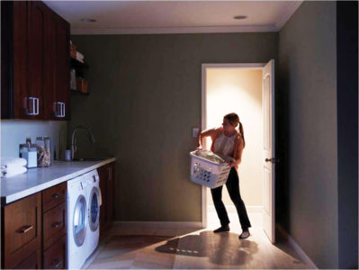 Woman trying to turn on lights while carrying laundry basket