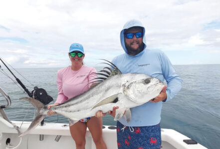 Man and woman holding roosterfish